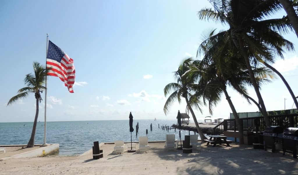palm trees along a beach in the florida keys with an american flag flying
