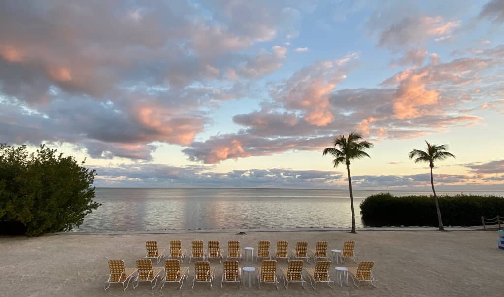 sunset in islamorada overlooking the gulf with palm trees and beach chairs along the water