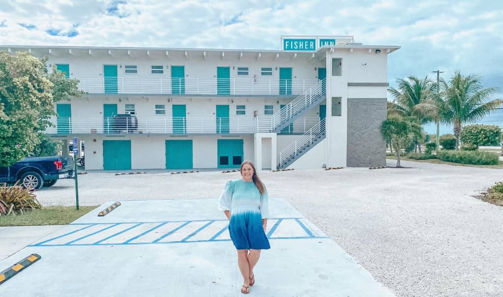 girl standing in front of a hotel in islamorada that says fisher inn on the top of the building
